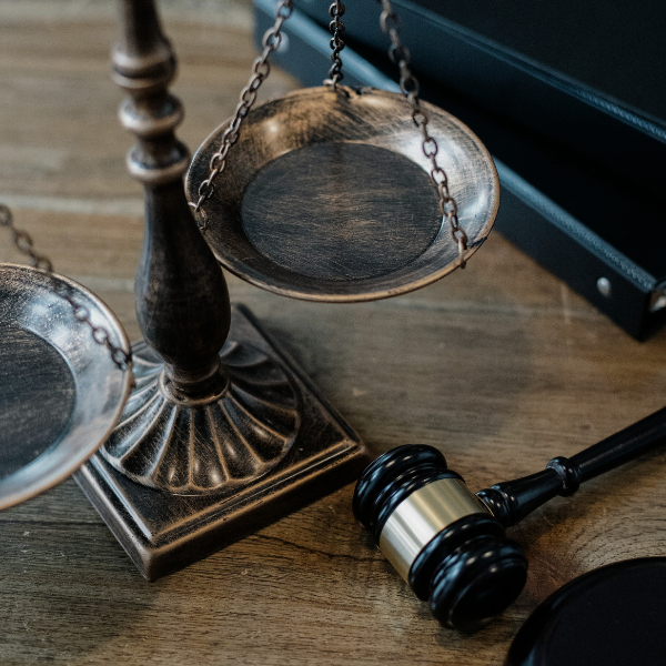 Balanza de la justicia de bronce junto a un mazo judicial sobre una mesa de madera, símbolo del derecho y la equidad.